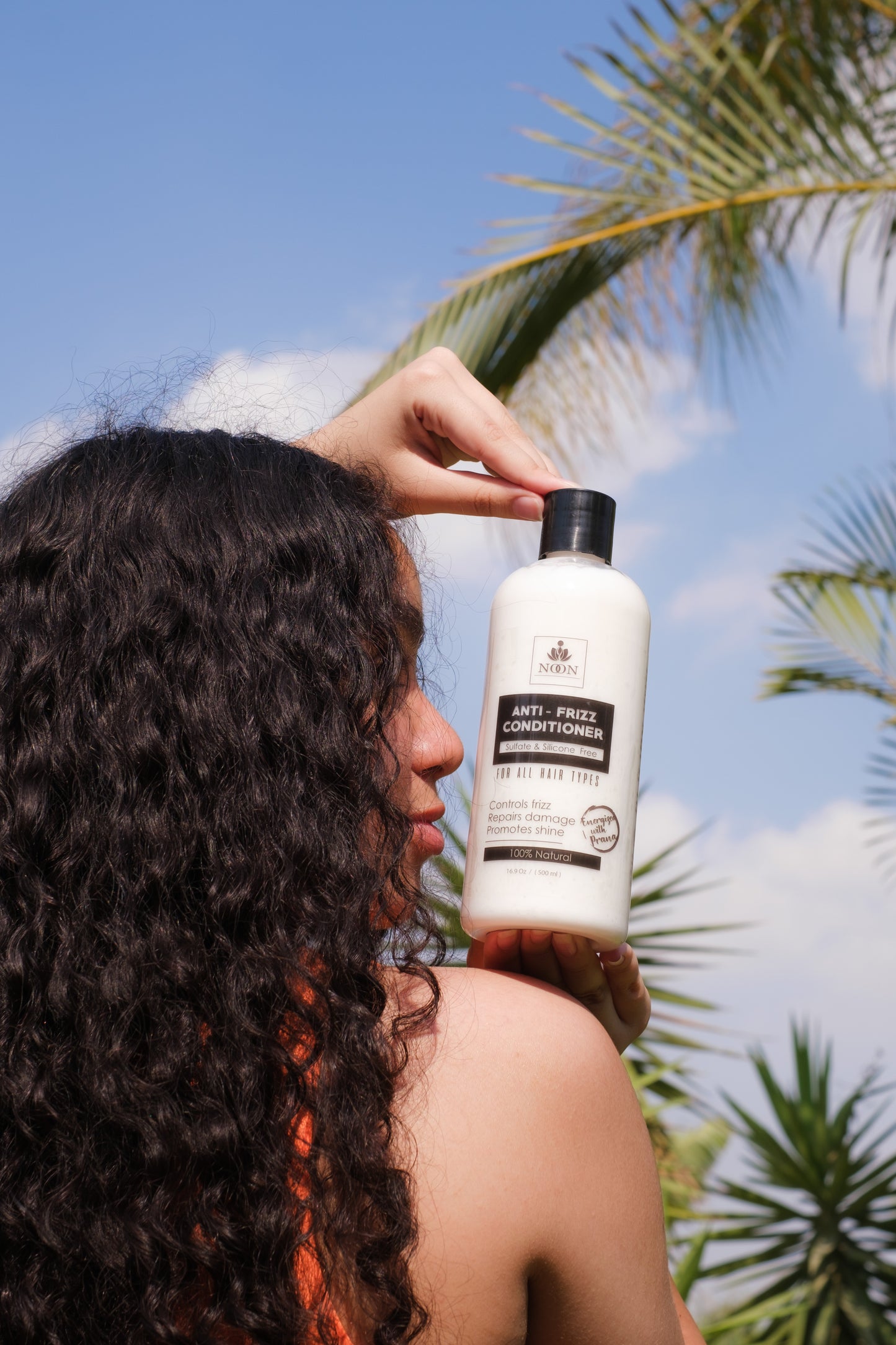 Curly hair girl holding anti frizz conditioner